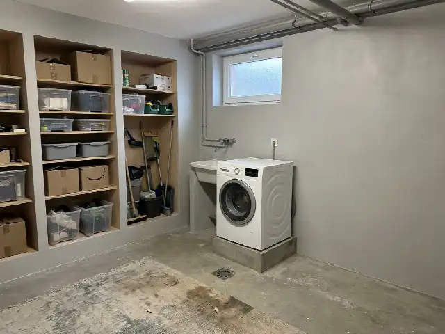 Droge, gerenoveerde kelder met rekken en een wasmachine